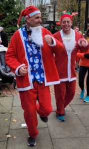 Two men running in santa suits