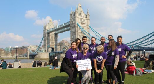 Walkers in purple t shirts finish the London Bridges walk near Tower Bridges in London